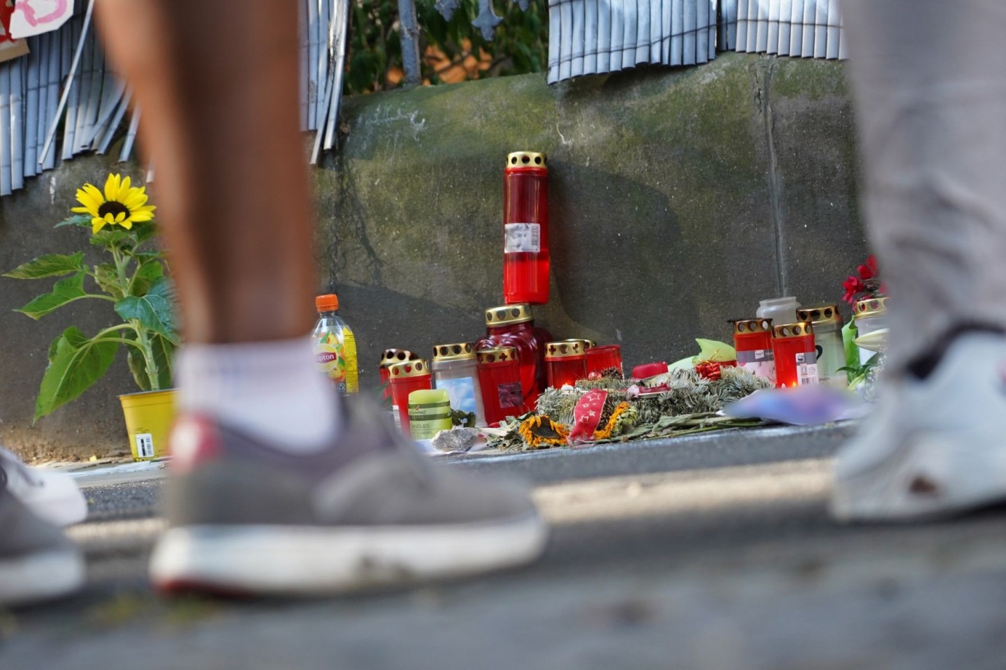 Menschen stehen in Dortmund vor einem Zaun, an dem mit Kerzen und Blumen des von der Polizei erschossenen Jugendlichen gedacht wird.