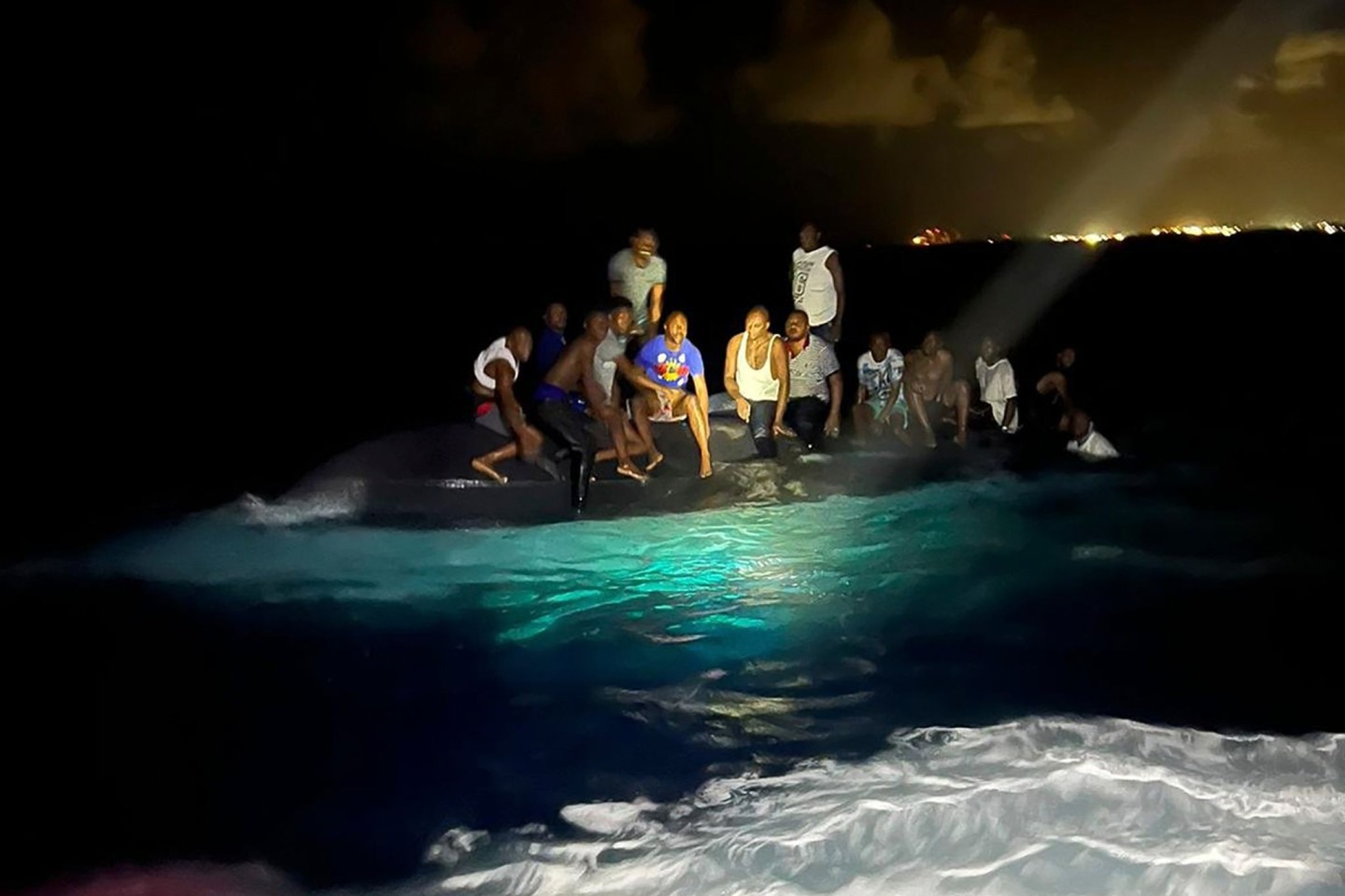Überlebende sitzen vor ihrer Rettung auf dem gekenterten Boot.